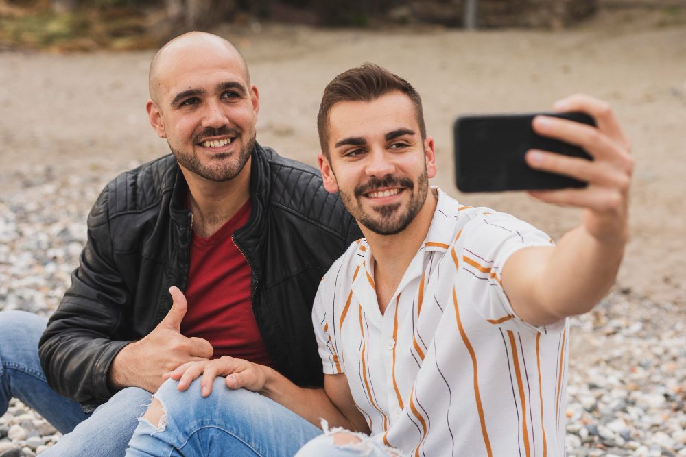 Imagen de dos hombres tomando una selfie en la playa.