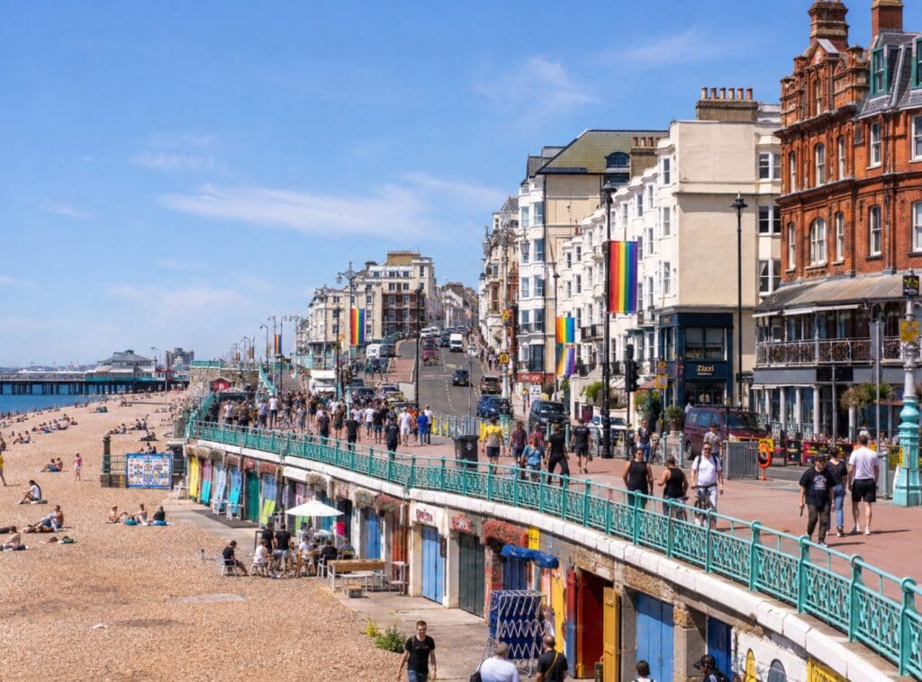 a sunny photograph of Brighton seafront looking towards Kemptown, with rainbow flags visible along the street