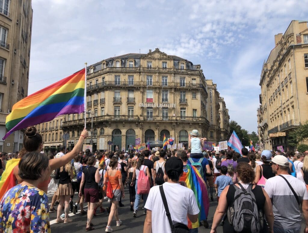 photo  familiale de la Marche des Fiertés de Metz traversant le centre-ville avec drapeaux colorés et public intergénérationnel