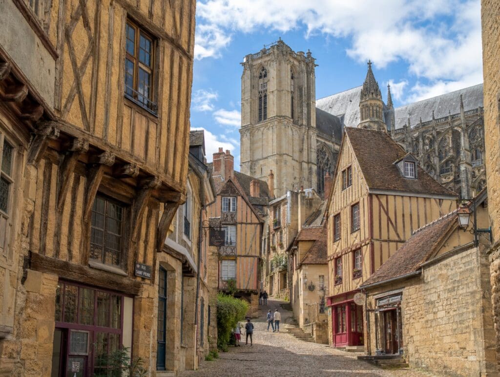 une photo de la Cité Plantagenêt avec ses maisons à pans de bois et la cathédrale Saint-Julien en arrière-plan