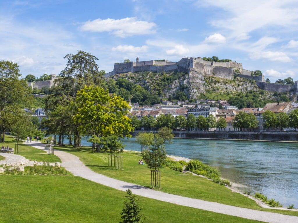 une photo du parc de la Gare-d'Eau (Besançon) avec le Doubs et les fortifications de la Citadelle en arrière-plan