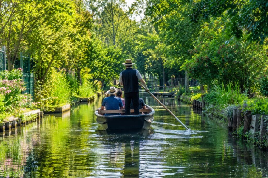une photo d’une barque traditionnelle naviguant entre les jardins verdoyants des Hortillonnages
