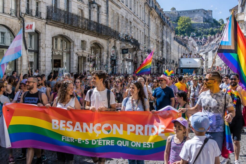 une photo familiale de la marche LGBTQIA+ de Besançon traversant La Boucle avec un public varié
